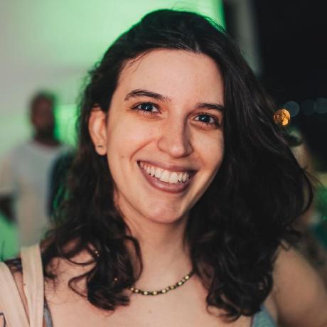 A foto mostra Brena O'Dwyer, uma mulher branca de cabelos castanhos ondulados, sorrindo. A foto mostra o rosto de Brena e um fundo verde borrado.